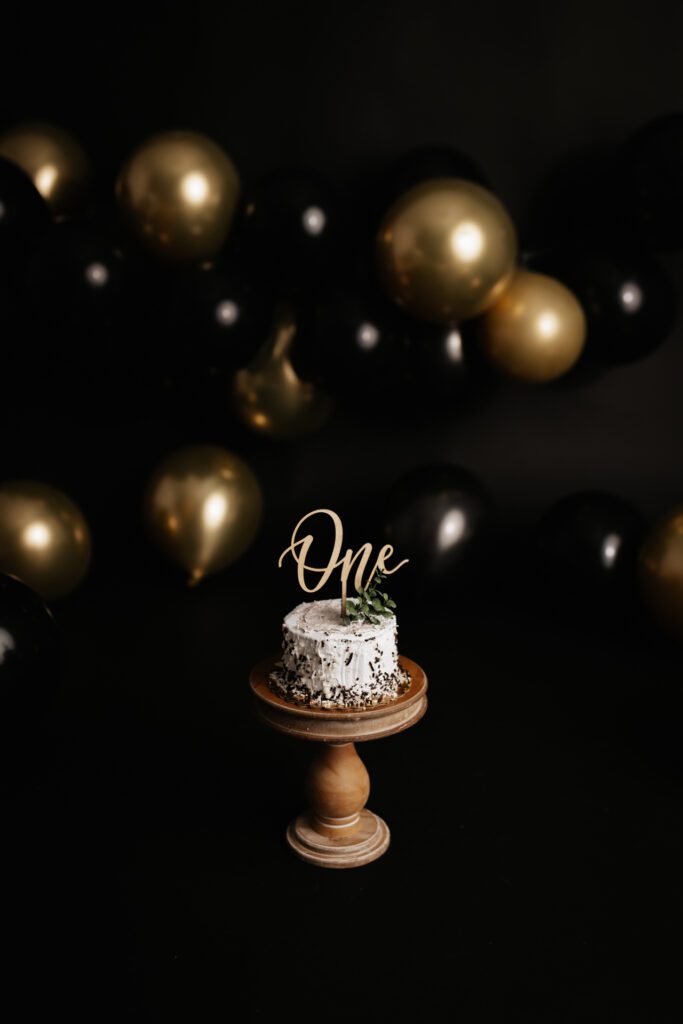 Chocolate cake with white frosting and gold ONE topper