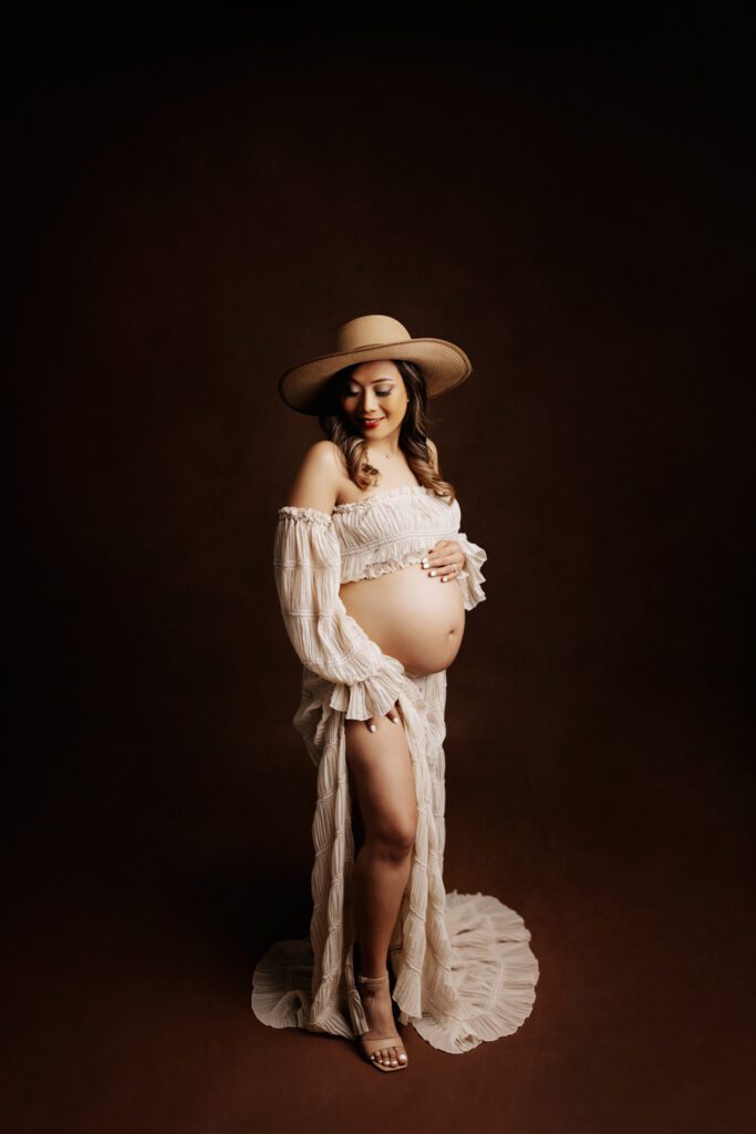 Woman in white two-piece maternity gown and sun hat
