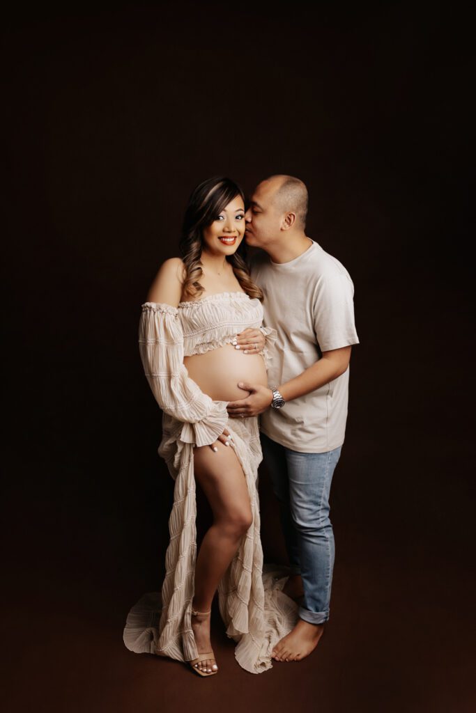 Husband kisses pregnant wife as they pose for Chicago maternity studio photography