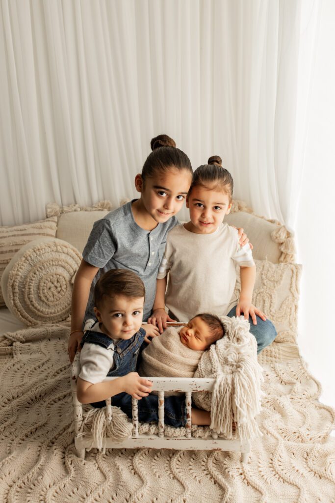 Siblings gather around their new baby brother in studio near Des Plaines Illinois