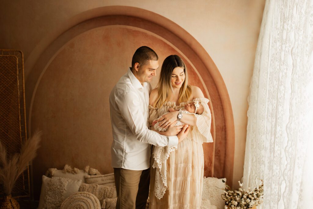 Parents cradle their newborn daughter in a cozy lifestyle studio setup near Chicago