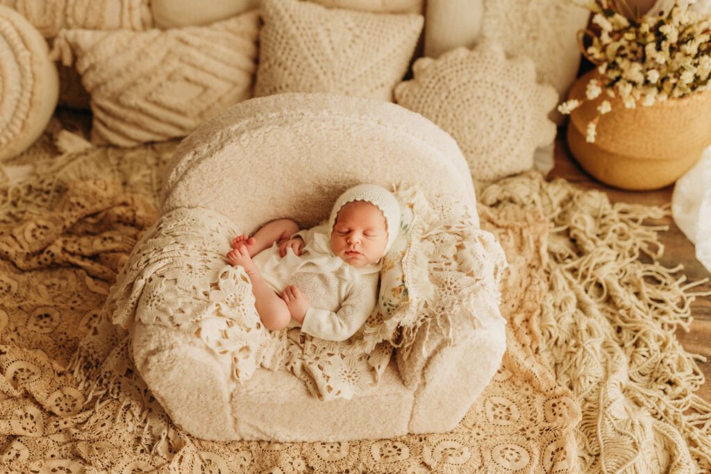 Baby girl curled up asleep on miniature couch in Long Grove Illinois photo studio