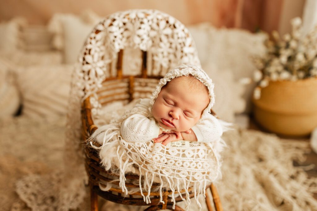 Baby asleep in wicker antique chair and basket with white lace