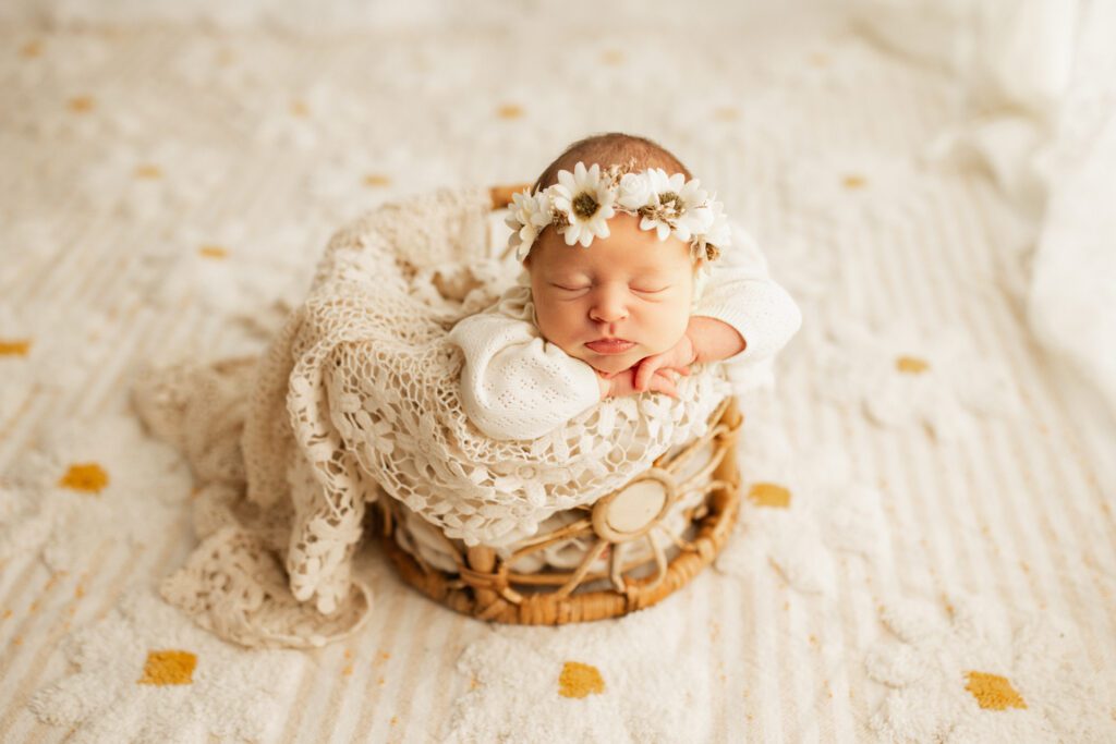Sleeping baby wearing flower crown and snuggled into a wicker basket