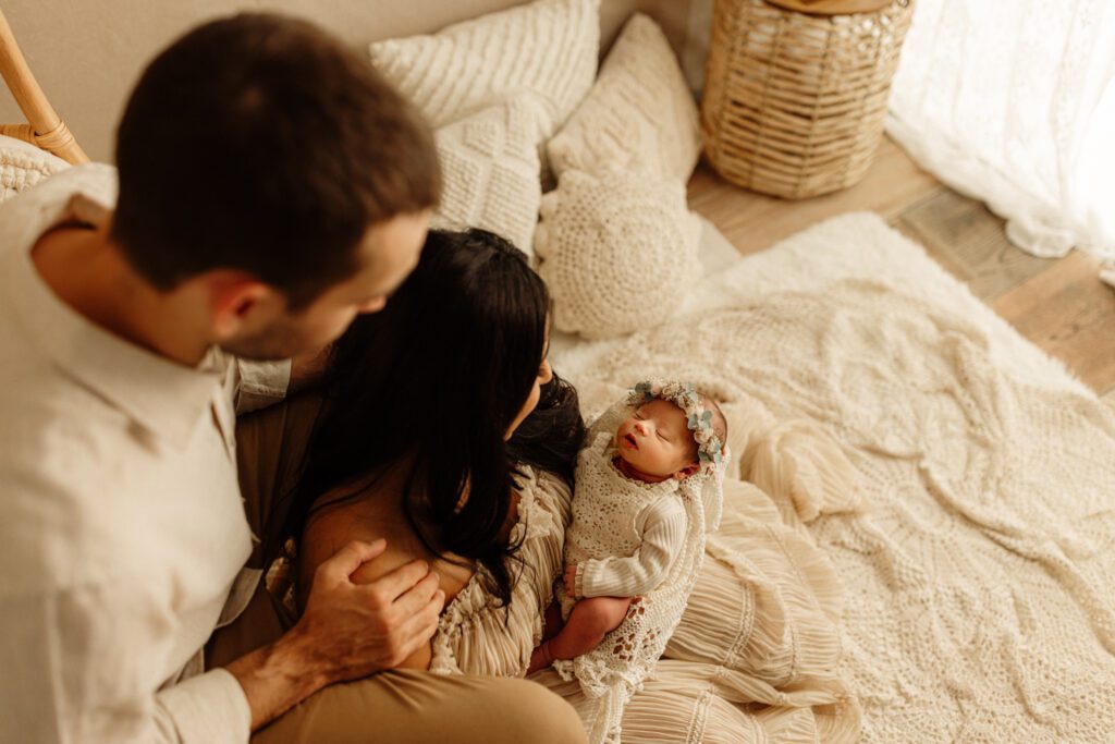 Parents seated on floor of lifestyle studio in Chicago, cradling their newborn daughter