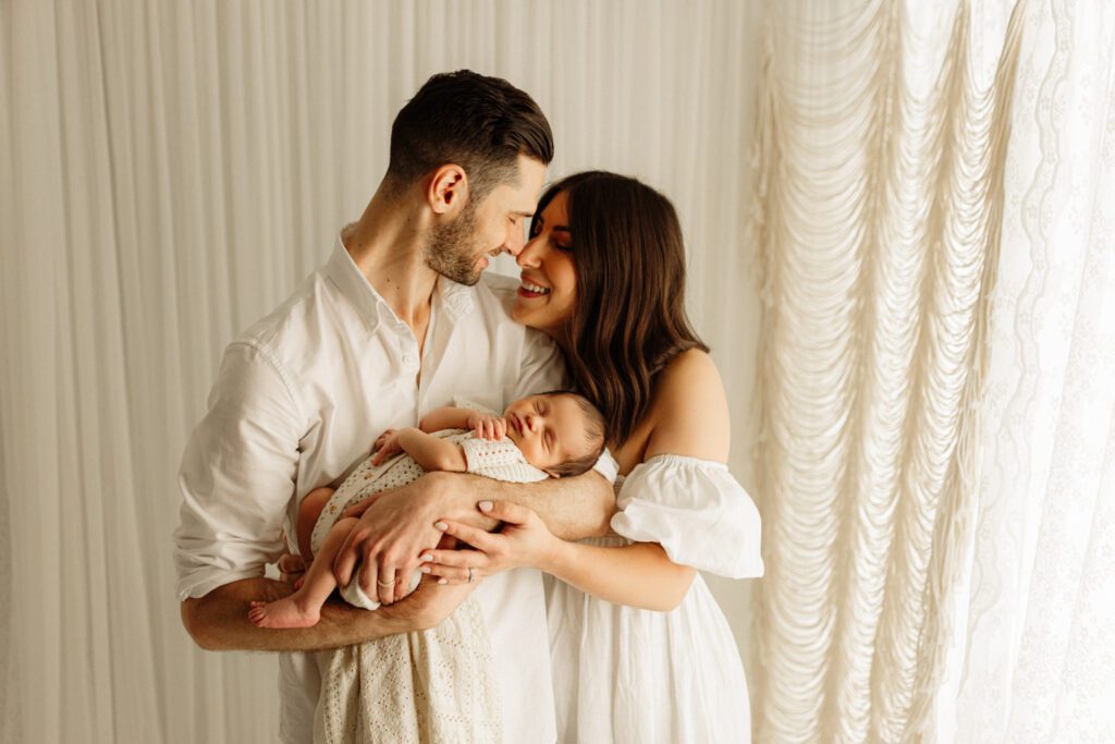 Mom and Dad gaze into each other's eyes while holding their newborn son