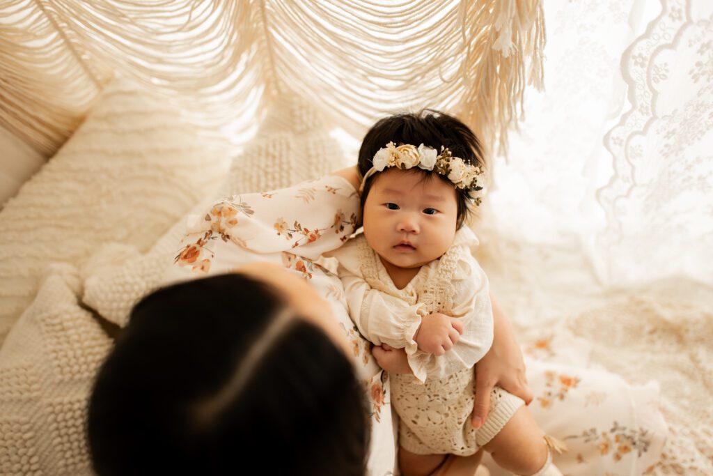 View from above as mom cradles baby girl in her arms during a 100 day celebration photoshoot