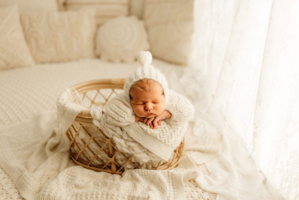 Palatine newborn nestled among blankets in a basket, fast asleep for his newborn portrait session