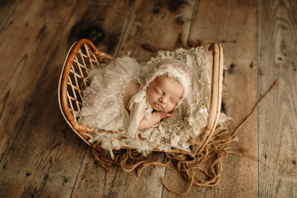 Infant girl in white polka-dot tulle dress on miniature antique bed