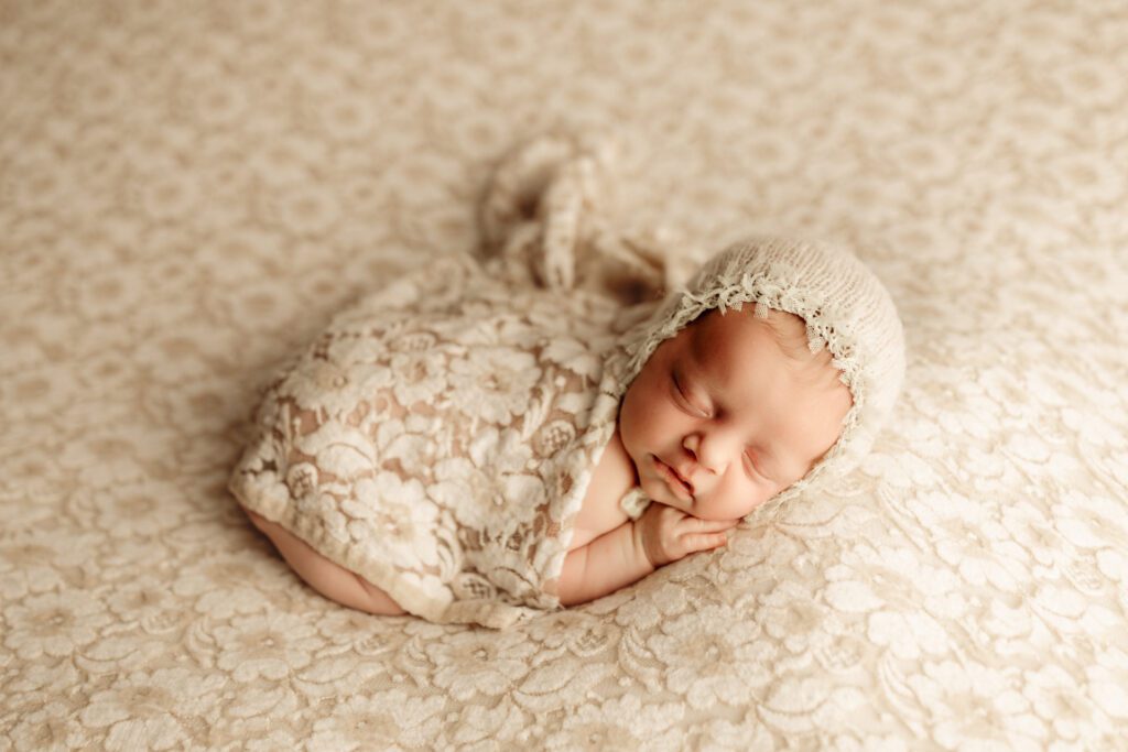 Newborn baby in pretty floral wrap and knitted cap, fast asleep in studio near Buffalo Grove Illinois