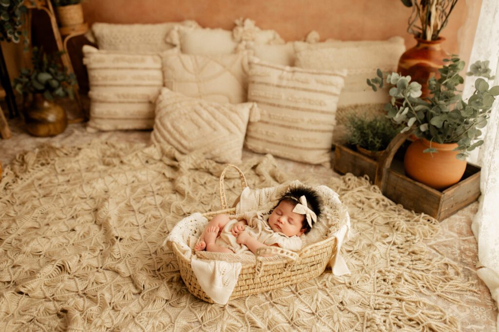 Sweet baby girl with fluffy black hair asleep in basket in a lifestyle studio setup