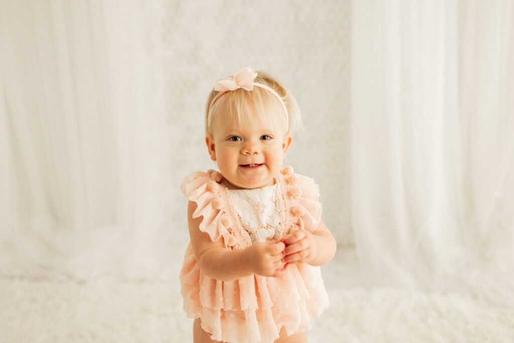 Baby pictures in Chicago, little girl in pink dress and bow smiling during her session