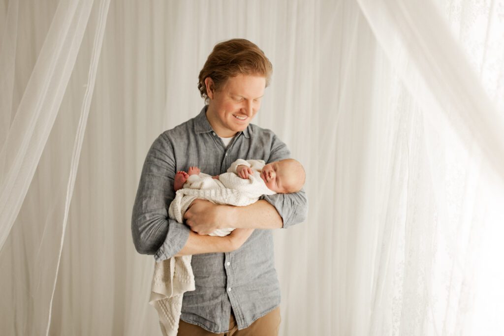 Dad smiled down at his newborn son as he cradles the baby in his arms