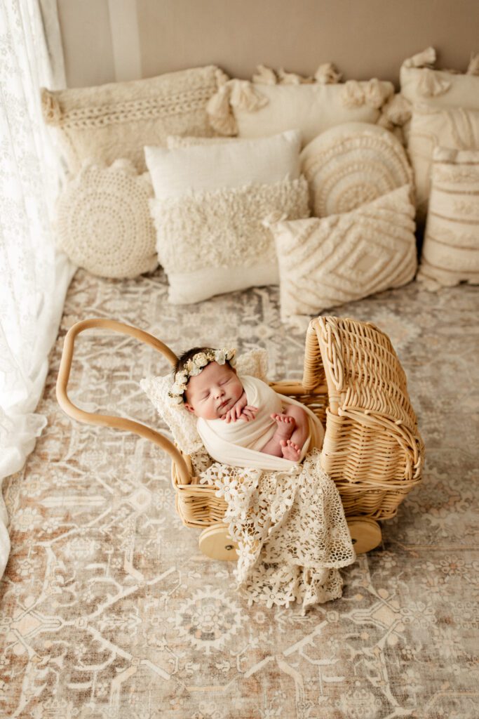 Baby girl in cream swaddle asleep in wicker pram in studio near Itasca Illinois