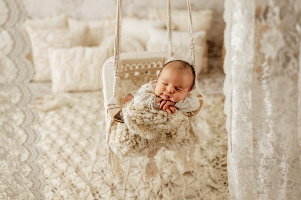 Baby boy asleep in macrame swing with a smile on his face