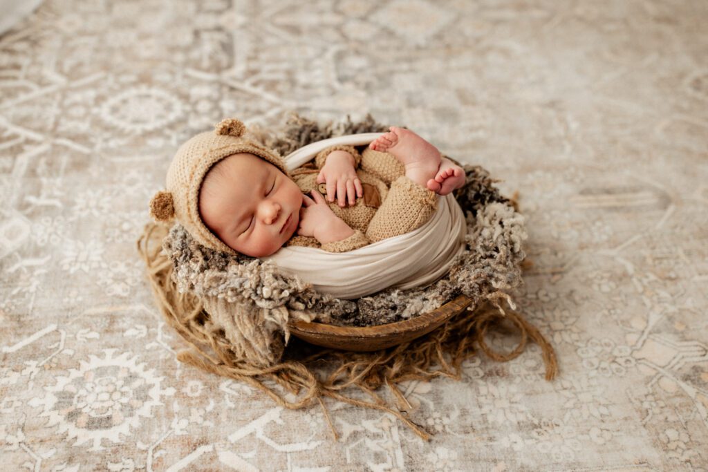 Baby boy in bear hat swaddled in a cozy basket